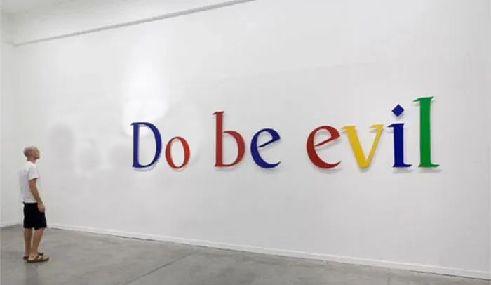 Man looking at the words "Do Be Evil" in Google font on the wall.
